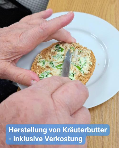 Nahezu intensiv wird eine Nahaufnahme gezeigt, in der zwei gealterte,wartungsvolle Hände Kräuterbutter auf eine Scheibe Brot streichen. Mit einem Messer wird die cremige Masse gleichmäßig verteilt, wobei die lebhaften grünen Kräuter sichtbar werden. Das Brot, großzügig getoastet, strahlt in einem warmen Goldbraun und bildet eine ansprechende Leinwand für die butterige Köstlichkeit. Der schlichte weiße Teller dient als ruhige Bühne, welche die Farben und Strukturen der Speise sowie der Hände harmonisch zur Geltung bringt.  Am unteren Bildrand prangt ein blauer Balken mit weißem Text: „Herstellung von Kräuterbutter – inklusive Verkostung“.